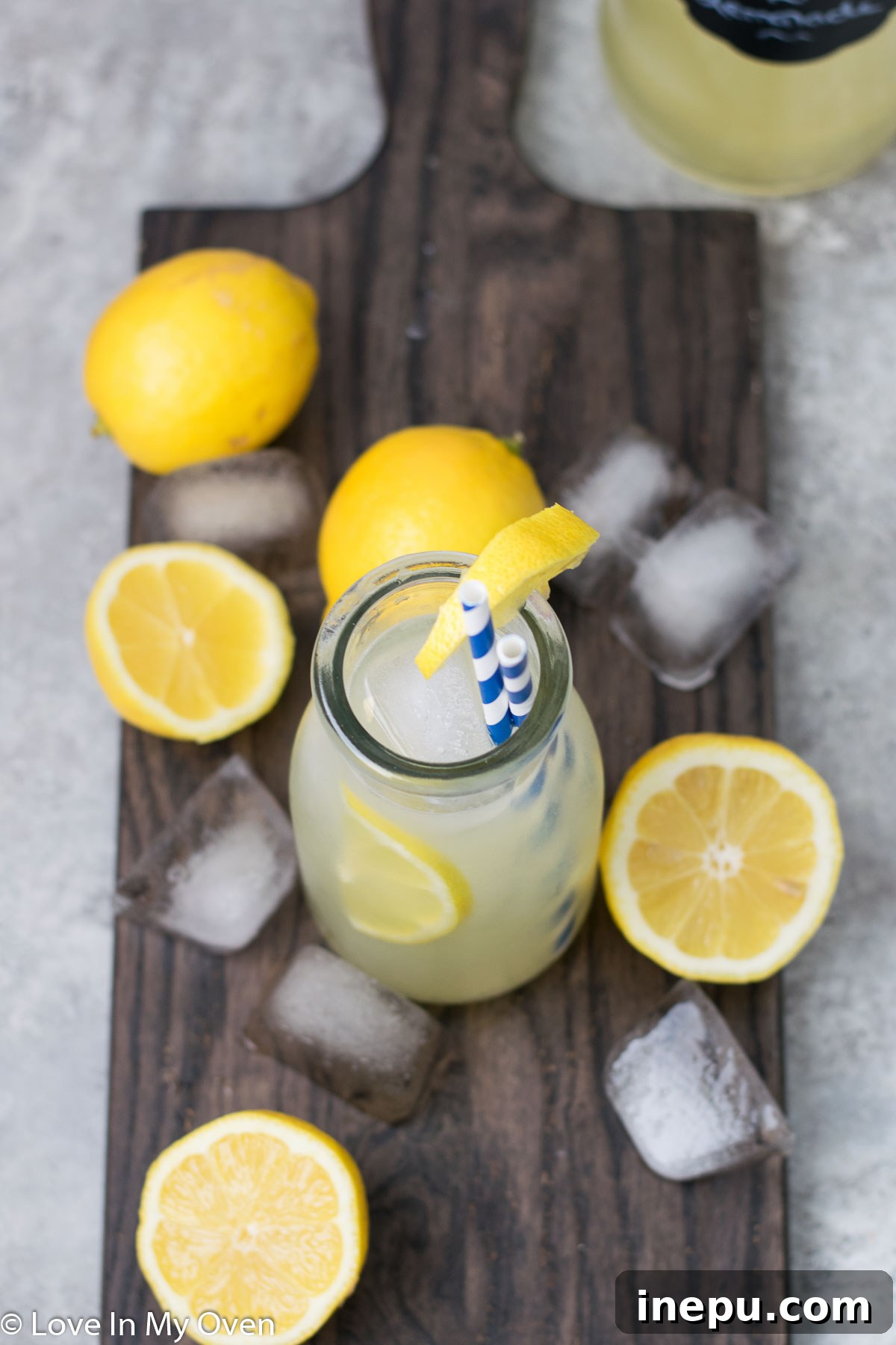 Effortless Honey Lemonade 7 A pitcher of honey lemonade on a wooden table with lemons and a glass