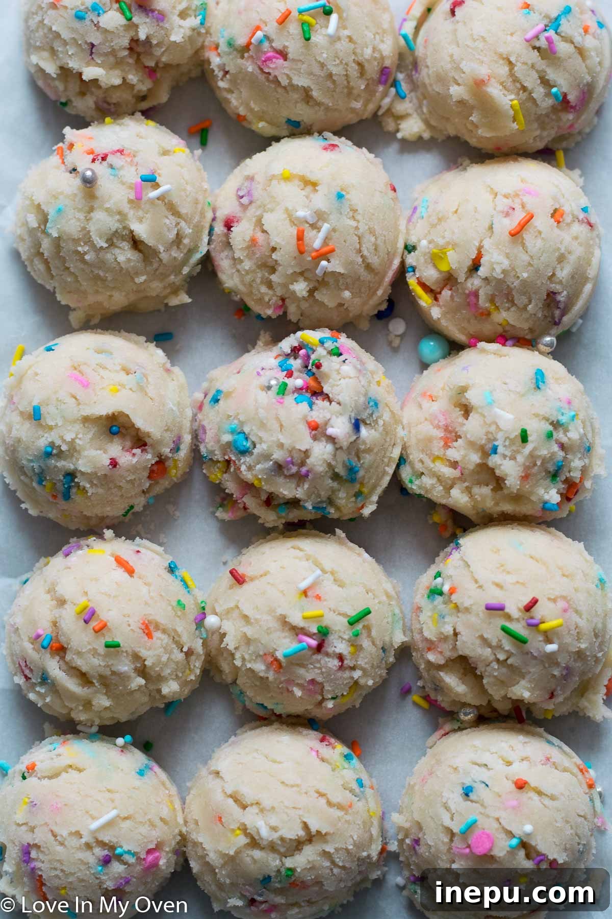 Whimsical Sprinkled Sugar Cookies 6 Scooped cookie dough balls with colorful sprinkles on an ungreased baking sheet, ready for the oven.