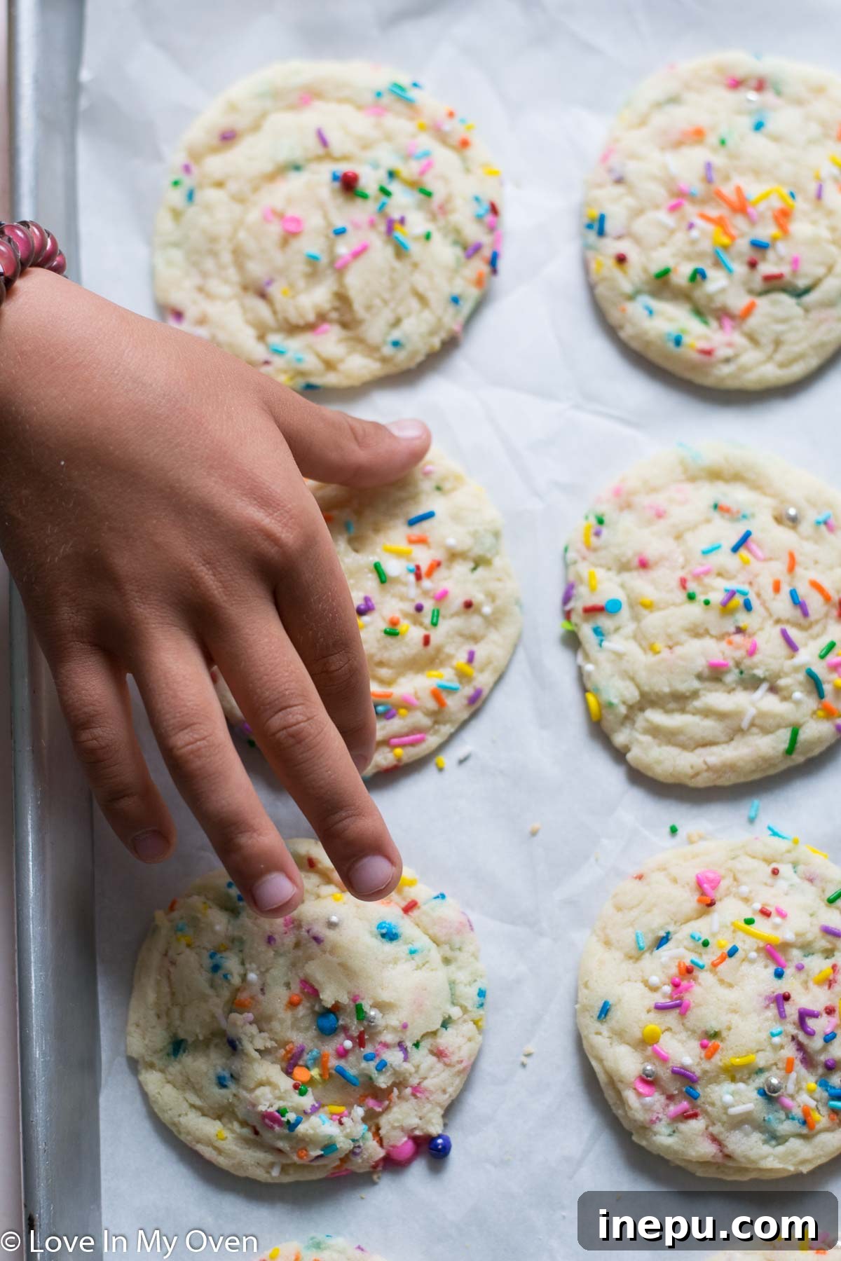 Whimsical Sprinkled Sugar Cookies 7 A stack of freshly baked sprinkle sugar cookies on a white plate, with a few loose sprinkles around.