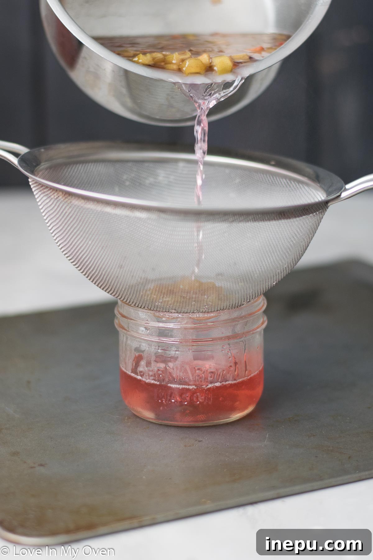 Refreshing Rhubarb Gimlet 4 Rhubarb simple syrup being strained into a jar