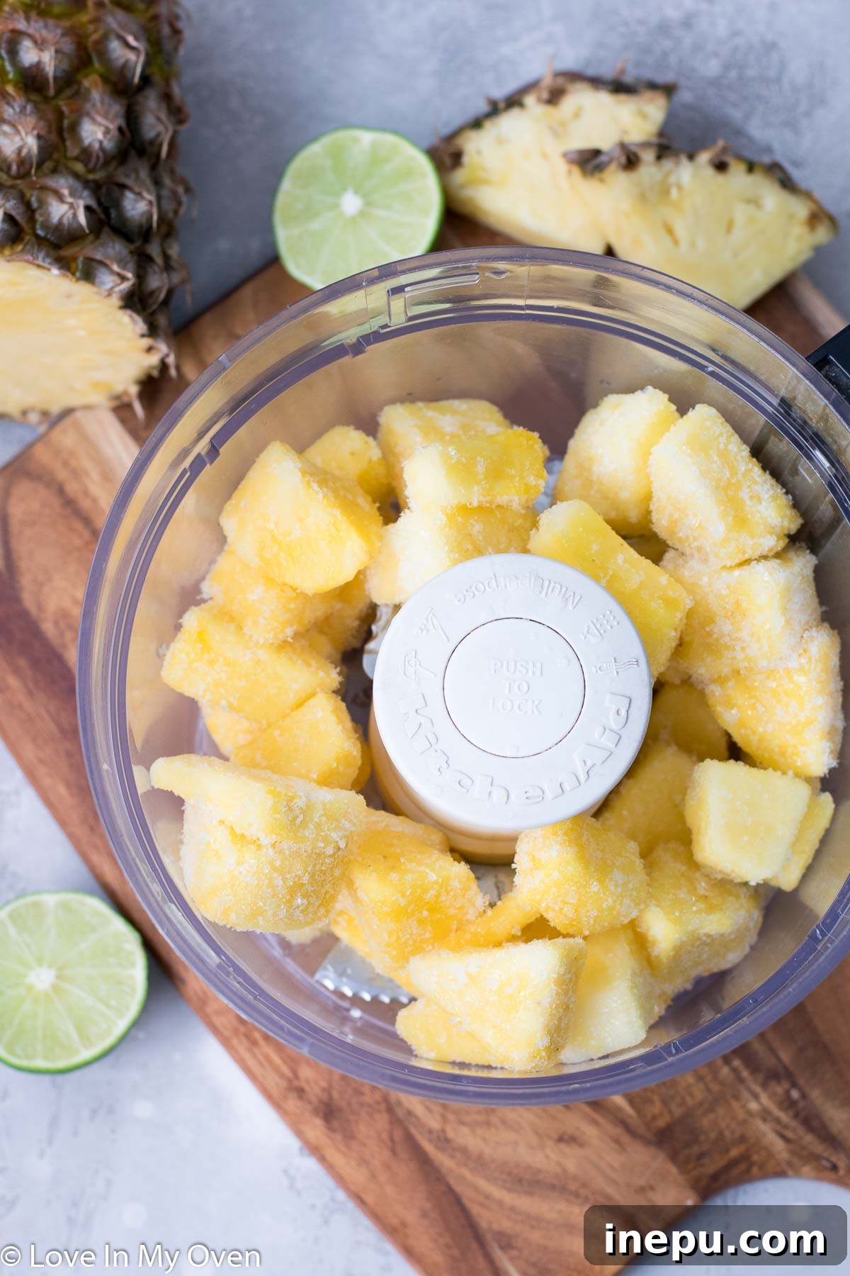 Tropical Pineapple Chill 4 Frozen pineapple chunks being added to a food processor.