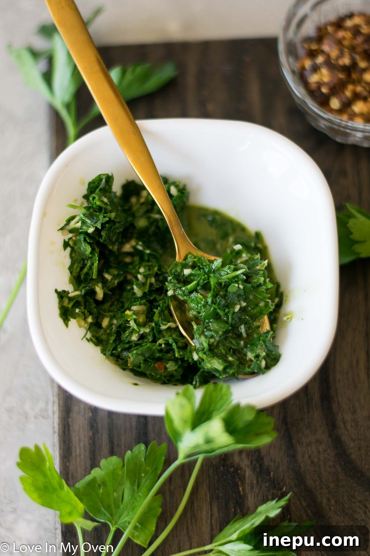 Smoky Turkey Thighs with Vibrant Chimichurri 4 Chimichurri sauce in a small white bowl next to fresh herbs and garlic.