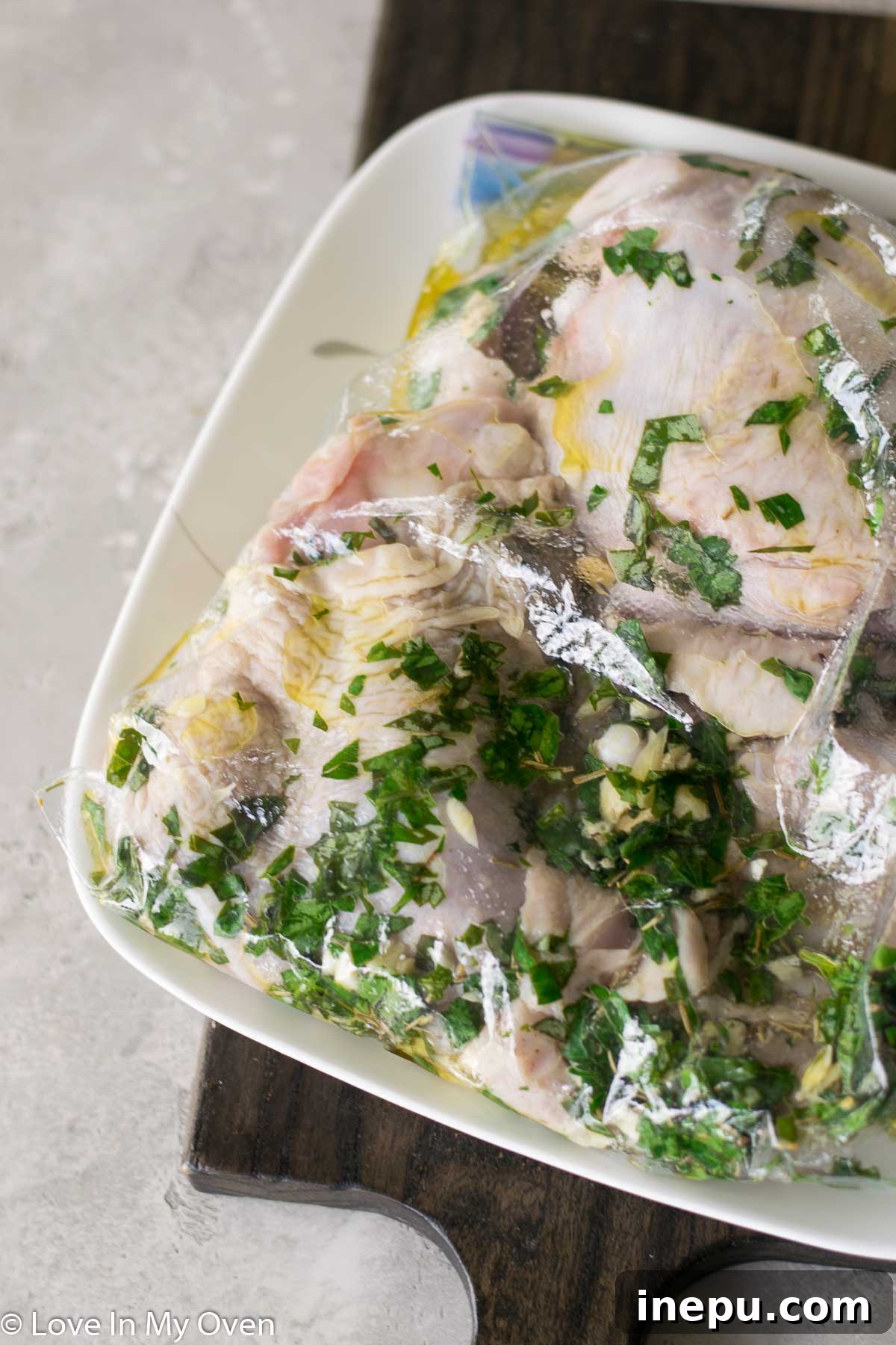 Smoky Turkey Thighs with Vibrant Chimichurri 5 Raw turkey thighs marinating in a resealable bag with herbs and lemon slices.