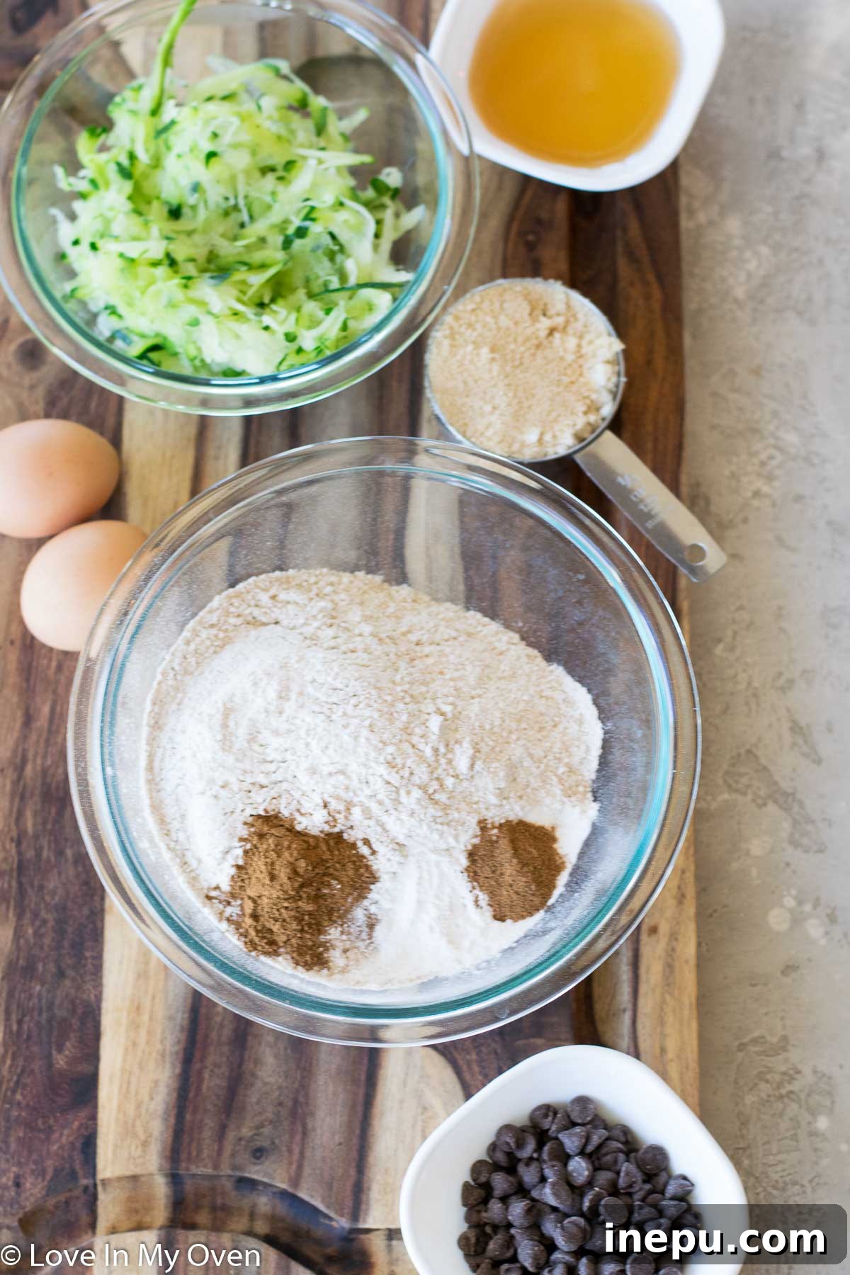A bowl of shredded zucchini with a colander, illustrating the moisture removal process for zucchini bread