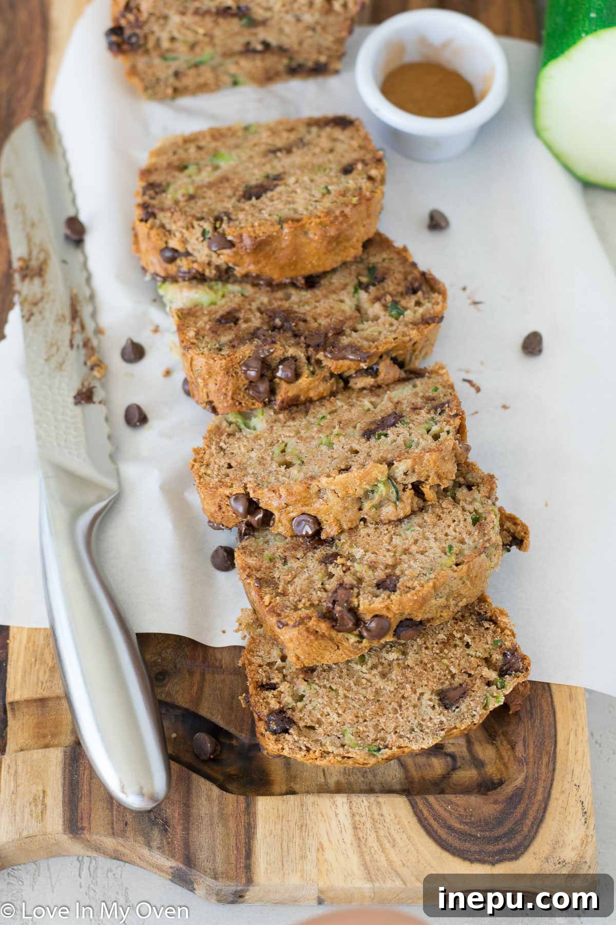 A slice of whole wheat zucchini bread on a cooling rack, showing its moist texture and chocolate chips