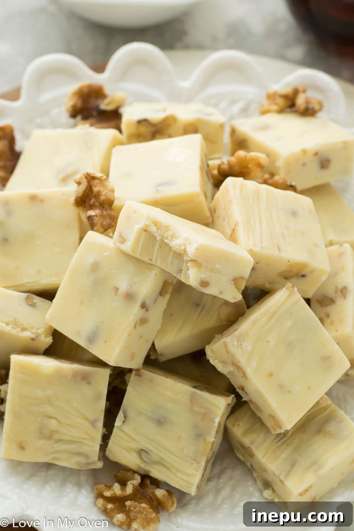 Close-up of golden brown maple walnut fudge slices, showcasing the creamy texture and chopped walnuts.