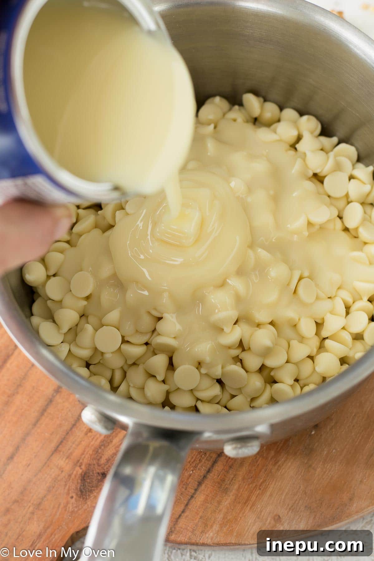 White chocolate chips and condensed milk melting together in a saucepan on the stove.