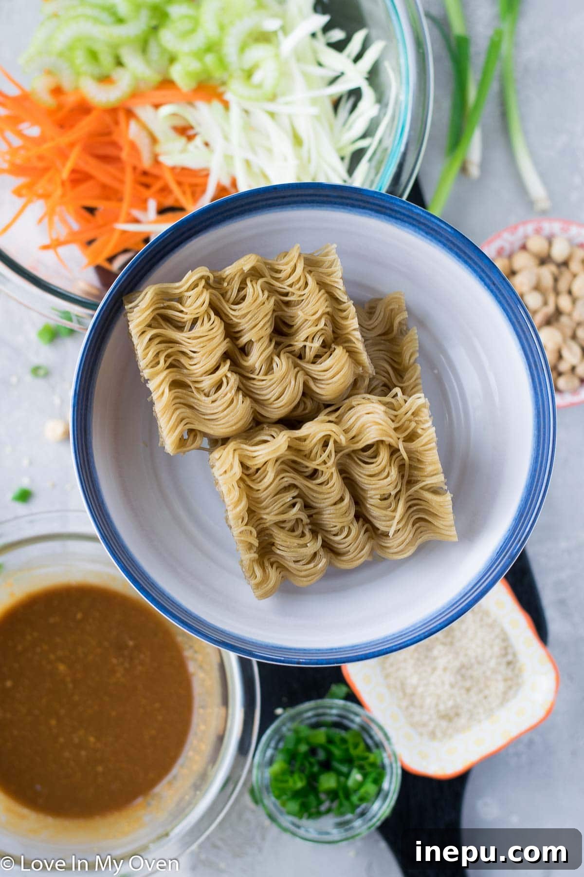 Prepared ingredients for sesame peanut noodle salad, including chopped vegetables