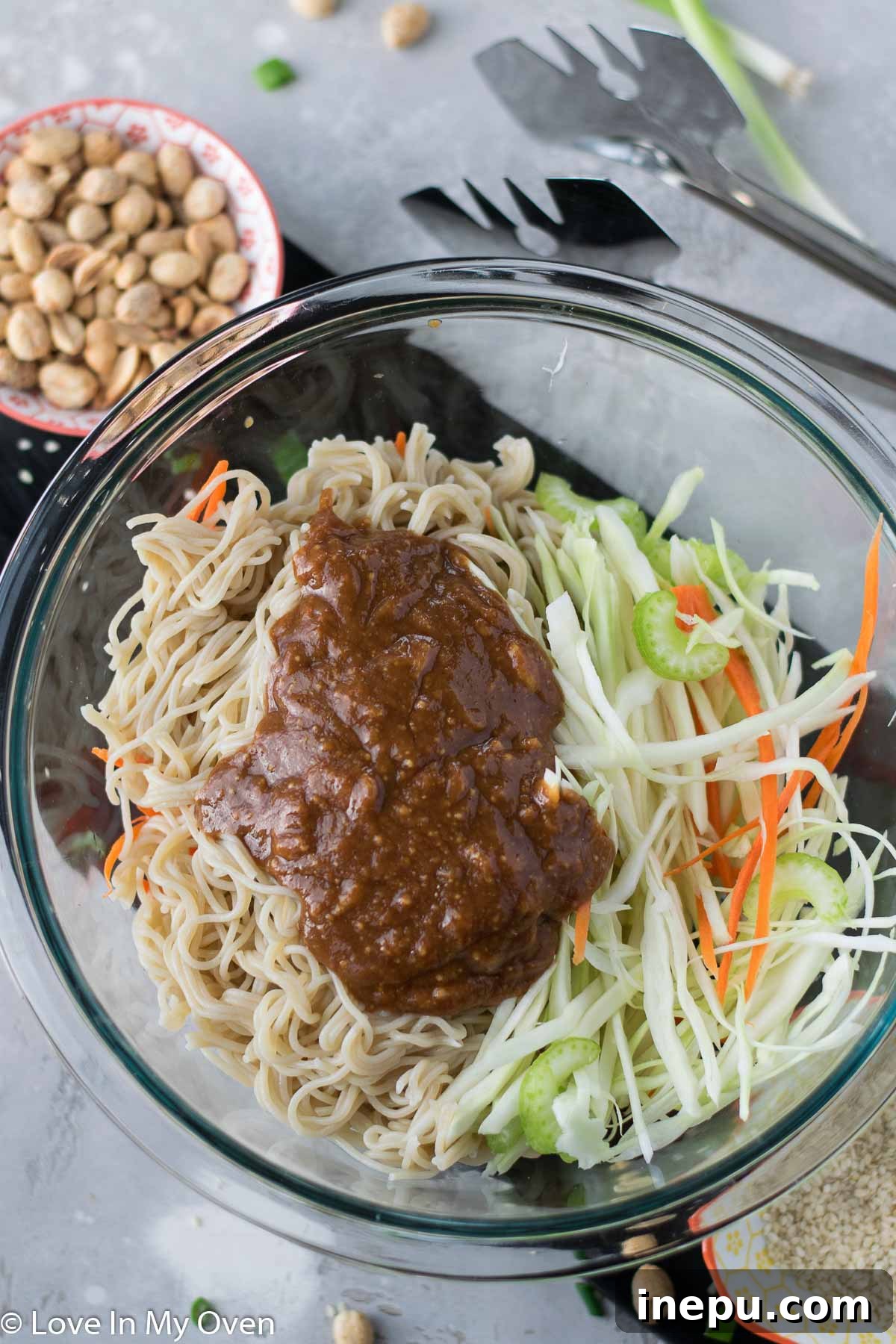 Sesame peanut noodles and vegetables mixed with the sauce in a bowl
