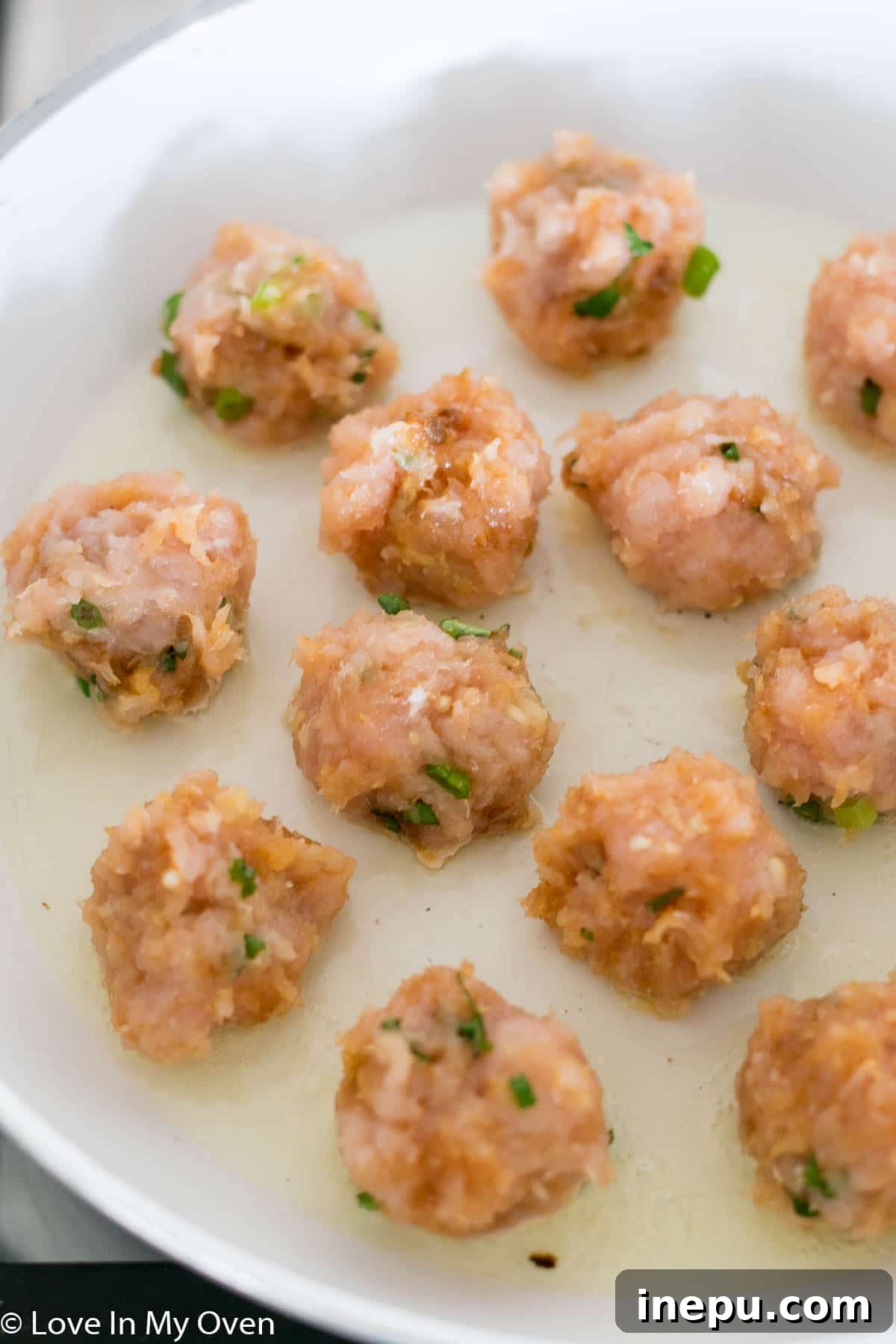 chicken meatballs cooking in pan