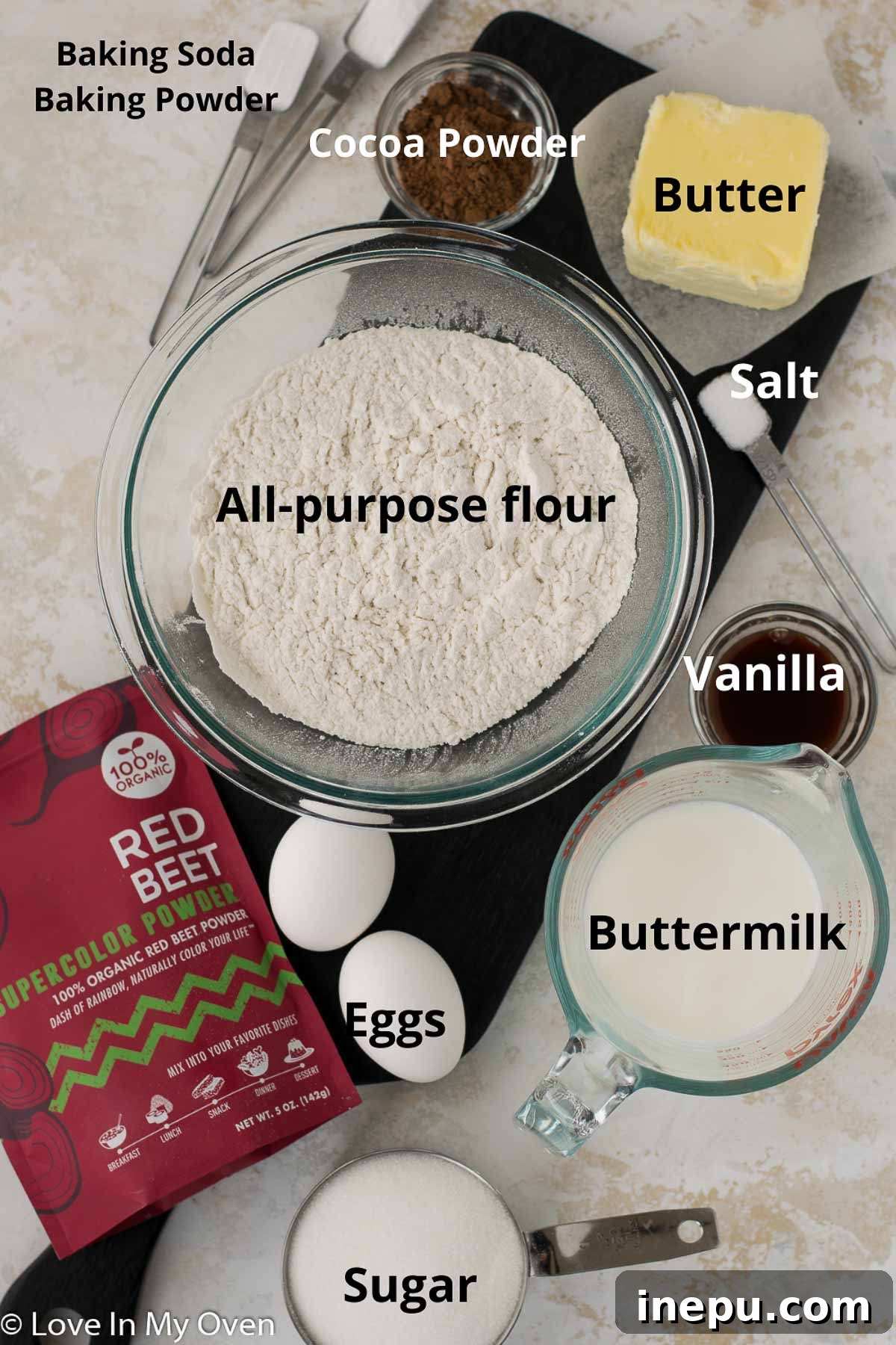 Various dry and wet ingredients laid out on a kitchen counter, ready for making red velvet cake.