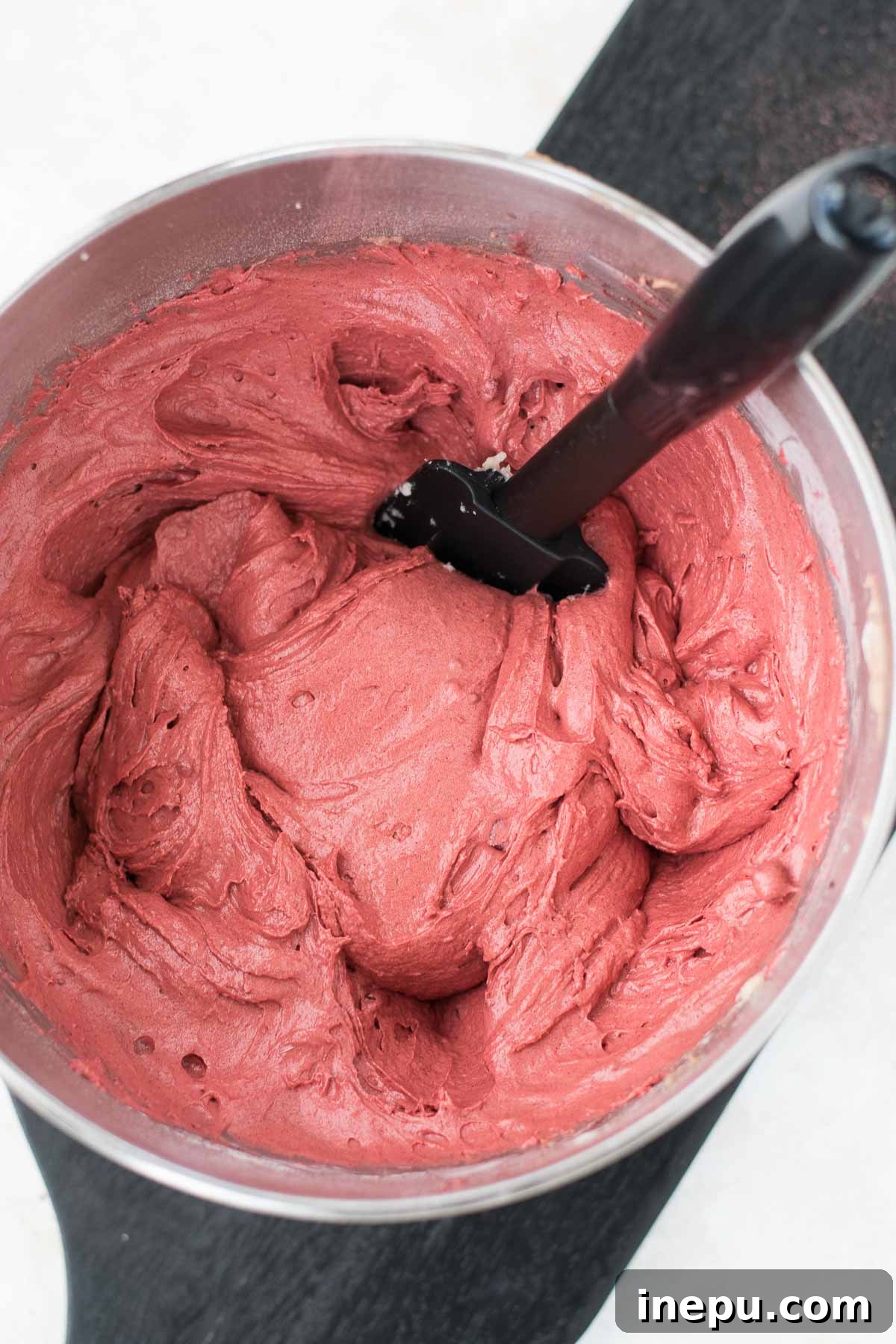Close-up of a bowl filled with vibrant red velvet cake batter.