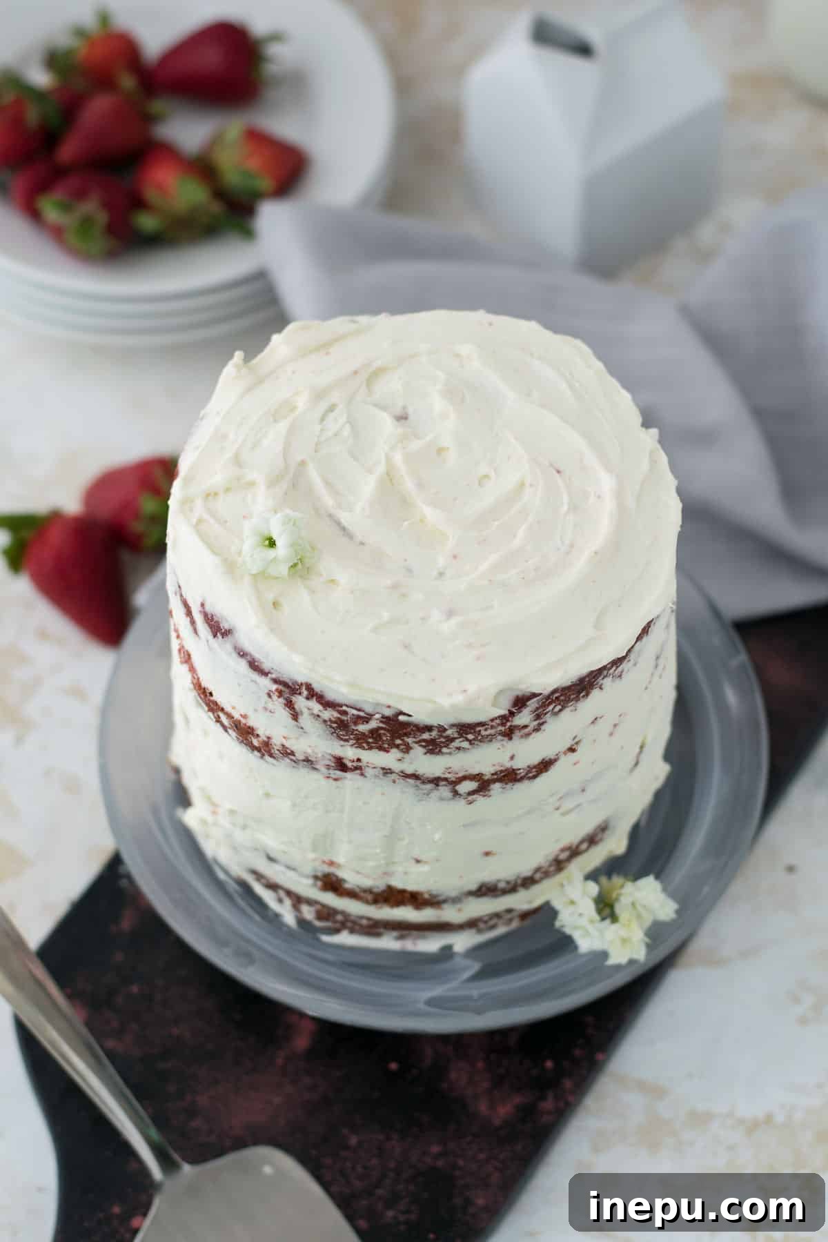 A beautifully frosted mini red velvet cake presented on a clean white surface.