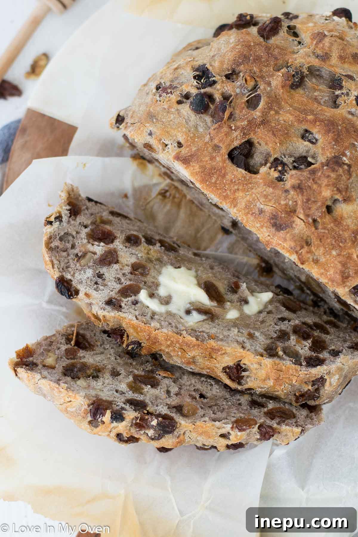 Close-up of a beautifully baked no-knead cinnamon raisin walnut bread loaf, showing its golden crust and delicious texture.