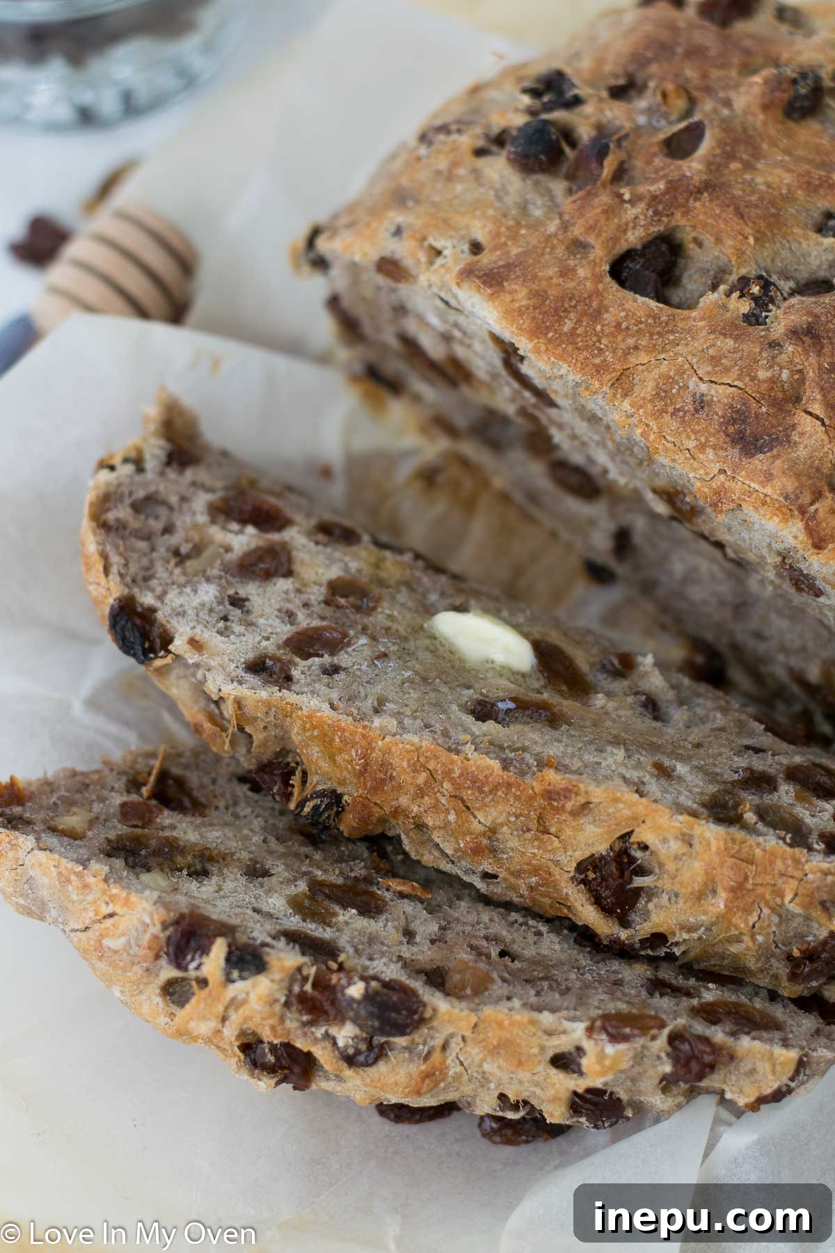 Hand reaching for a slice of freshly baked cinnamon raisin walnut bread on a cutting board.
