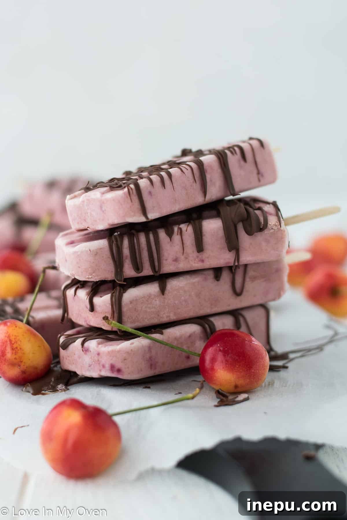 Homemade Greek Yogurt Cherry Popsicles with a chocolate drizzle, a perfect healthy summer treat.
