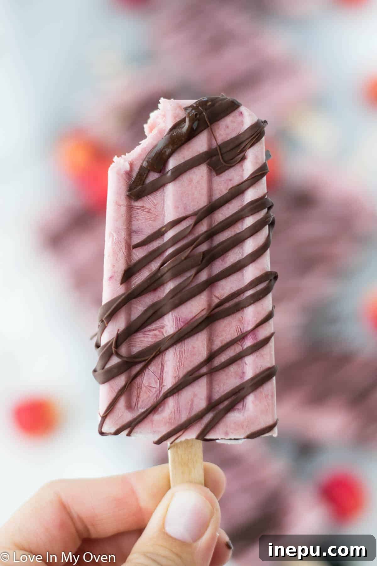 Overhead shot of two delicious Greek yogurt cherry popsicles, garnished with fresh cherries.