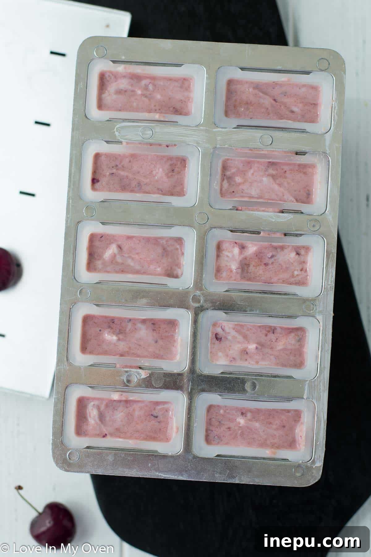 Fully frozen Greek yogurt cherry popsicles in their molds.