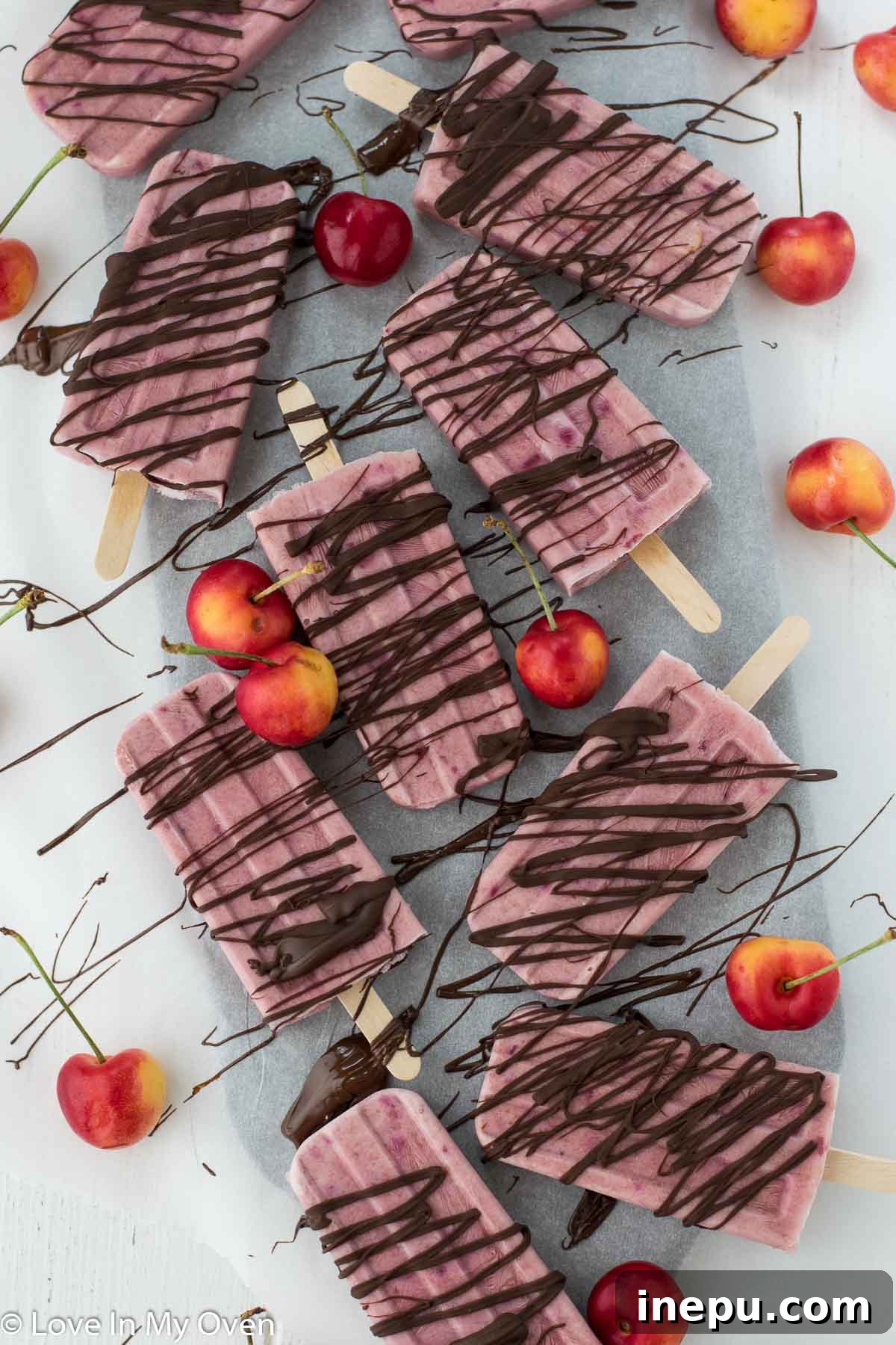 Greek yogurt cherry popsicles with a delicious chocolate drizzle.