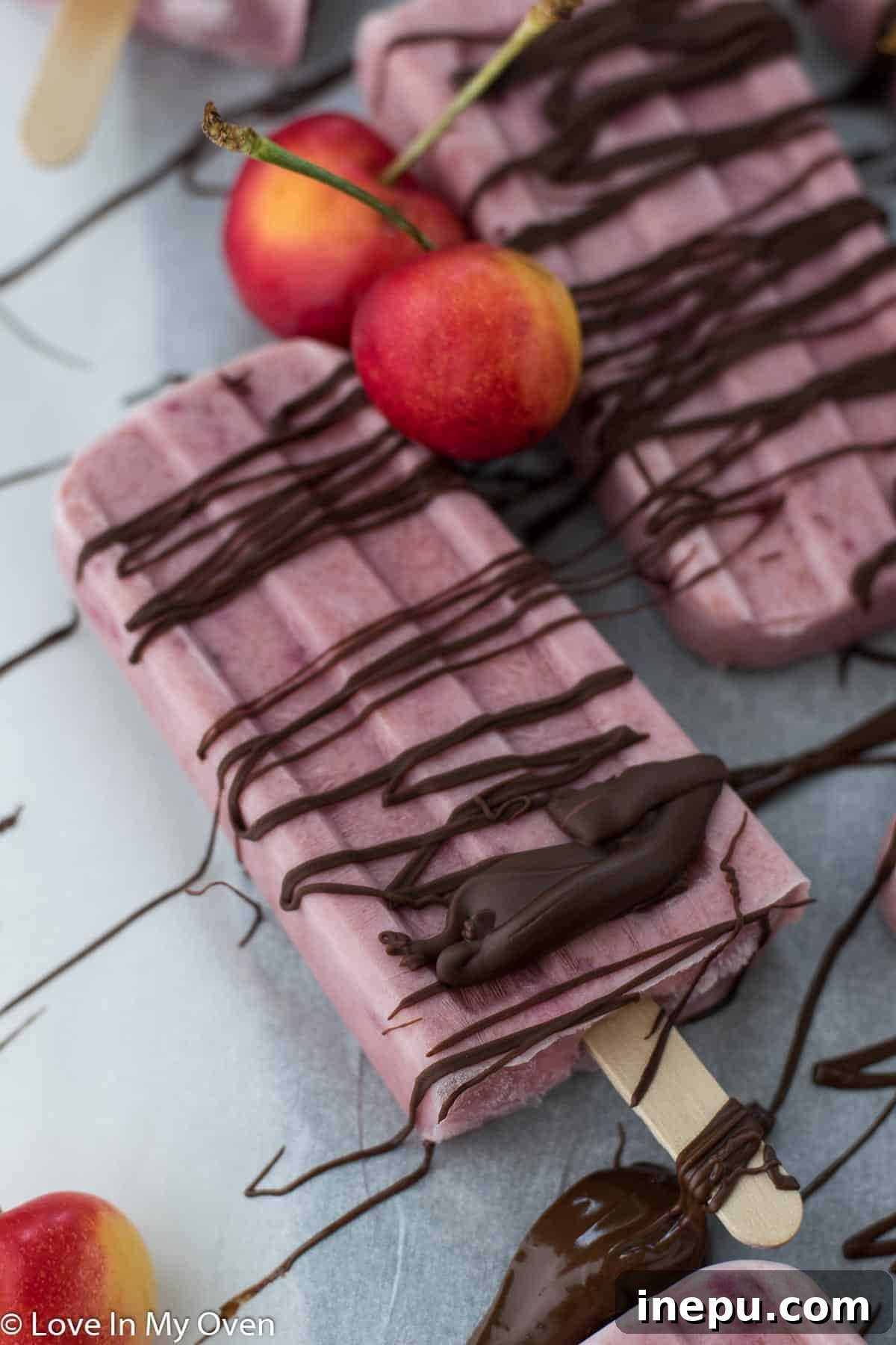 Two beautifully presented Greek yogurt cherry popsicles, ready to eat.