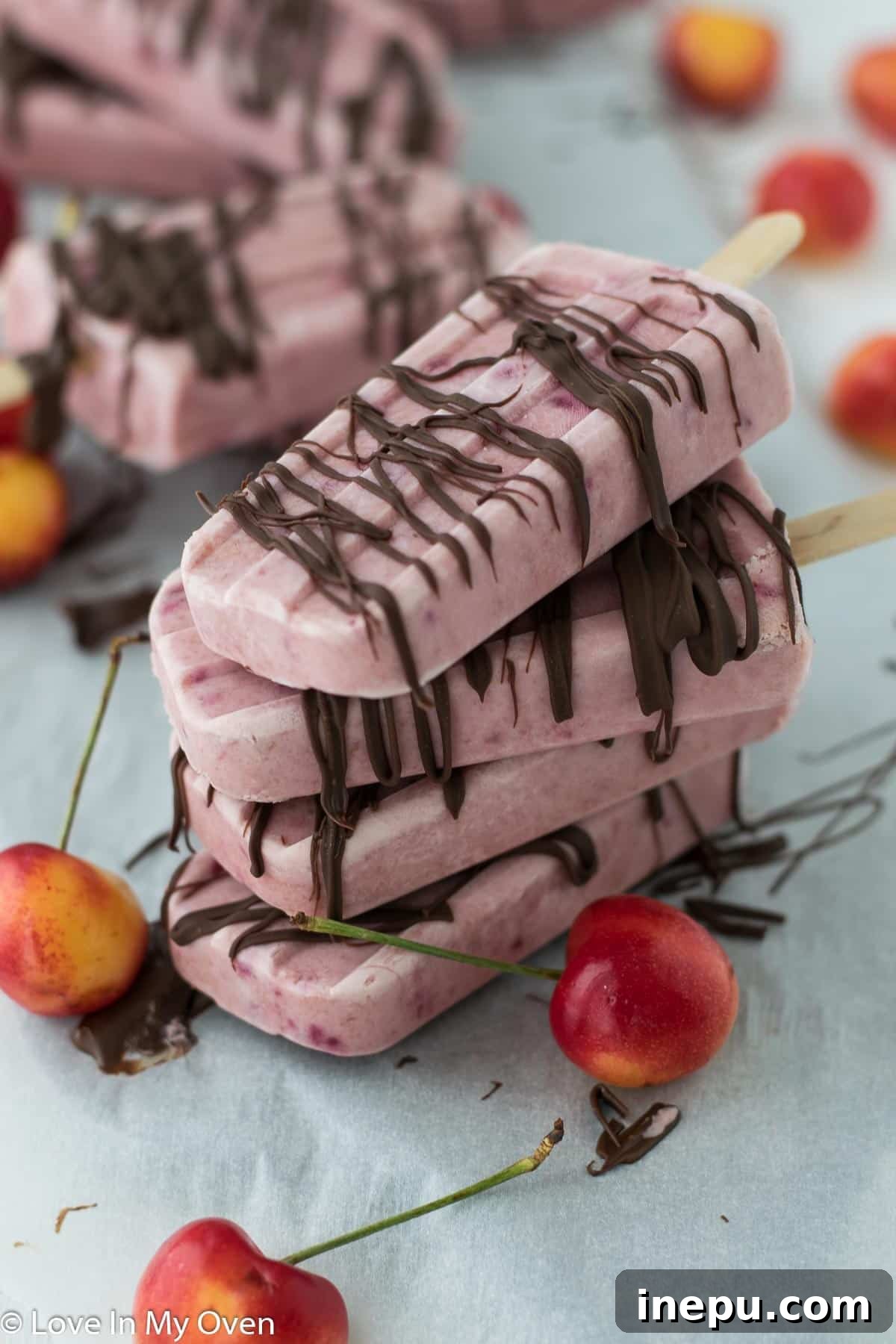 A tray of Greek yogurt cherry popsicles, some plain, some with chocolate drizzle.
