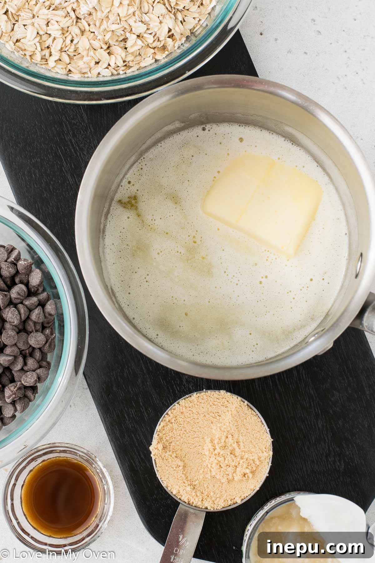 Ingredients laid out for gluten free oatmeal fudge bars: oats, brown sugar, butter, chocolate chips, condensed milk, vanilla