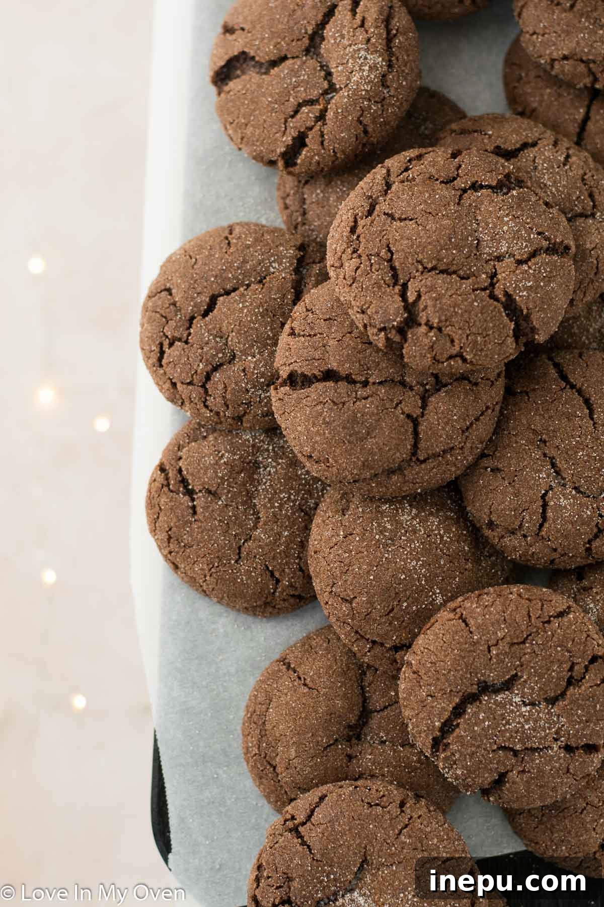 A stack of baked chocolate snickerdoodles with a bite taken out, showing the chewy interior
