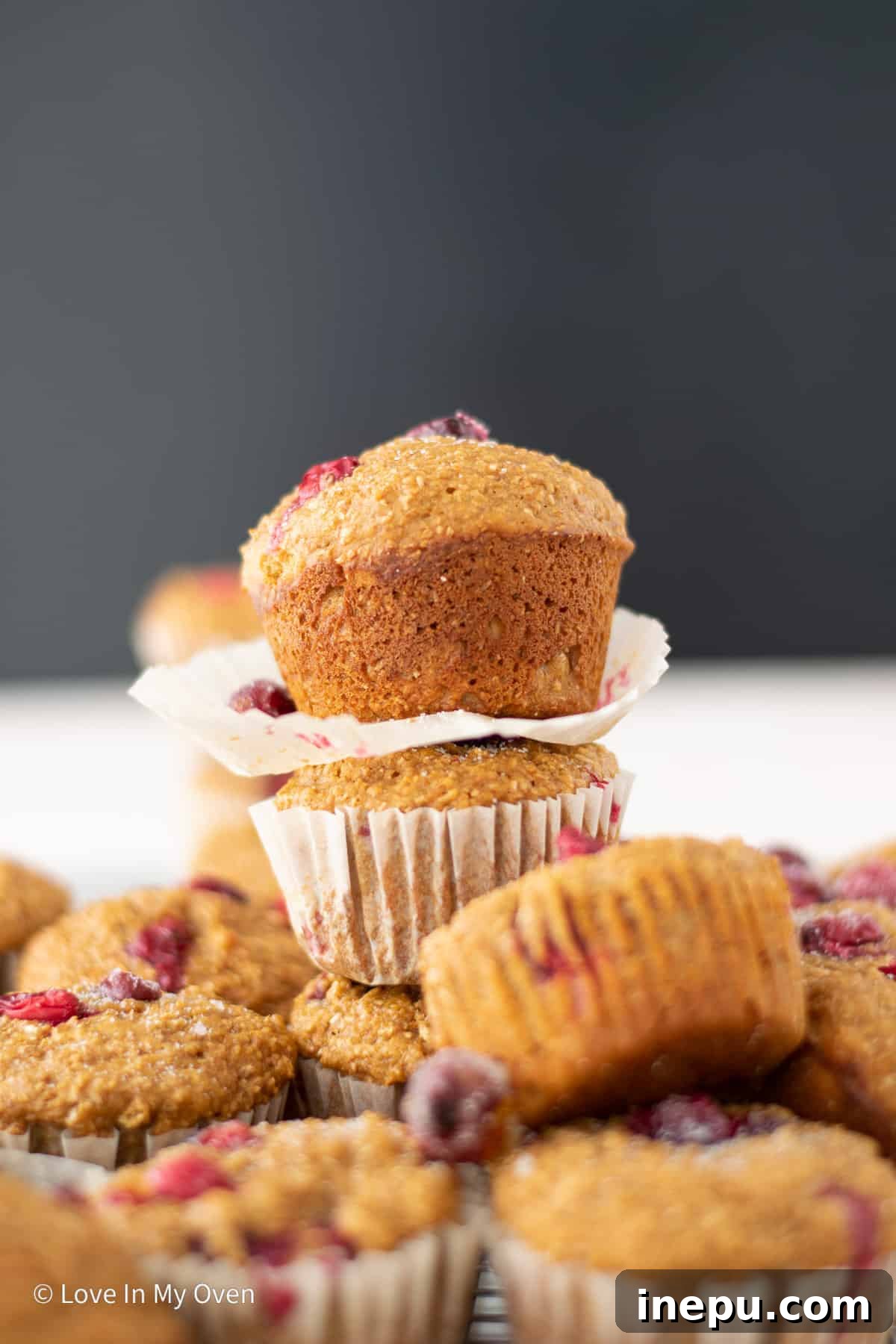 A stack of freshly baked cranberry bran muffins on a white plate