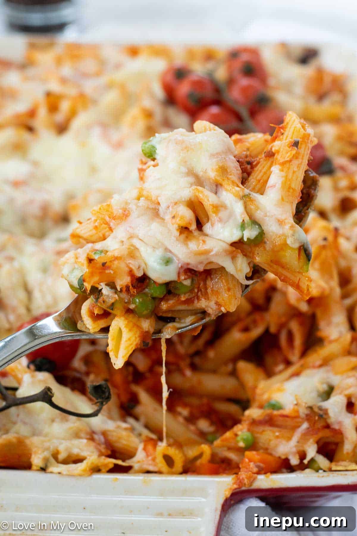 Cheesy Baked Veggie Pasta 7 A serving of the cheesy veggie pasta bake on a plate with a fork, showing the melted cheese and vegetables