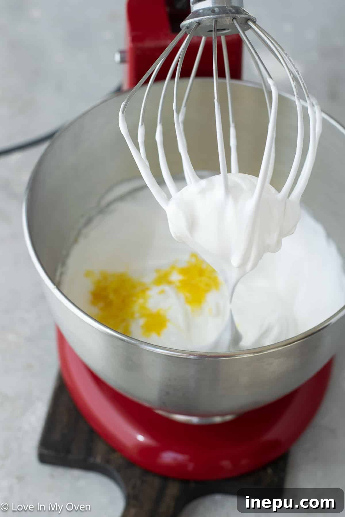 Stiff, glossy meringue peaks in a mixing bowl, ready for flavoring and piping.