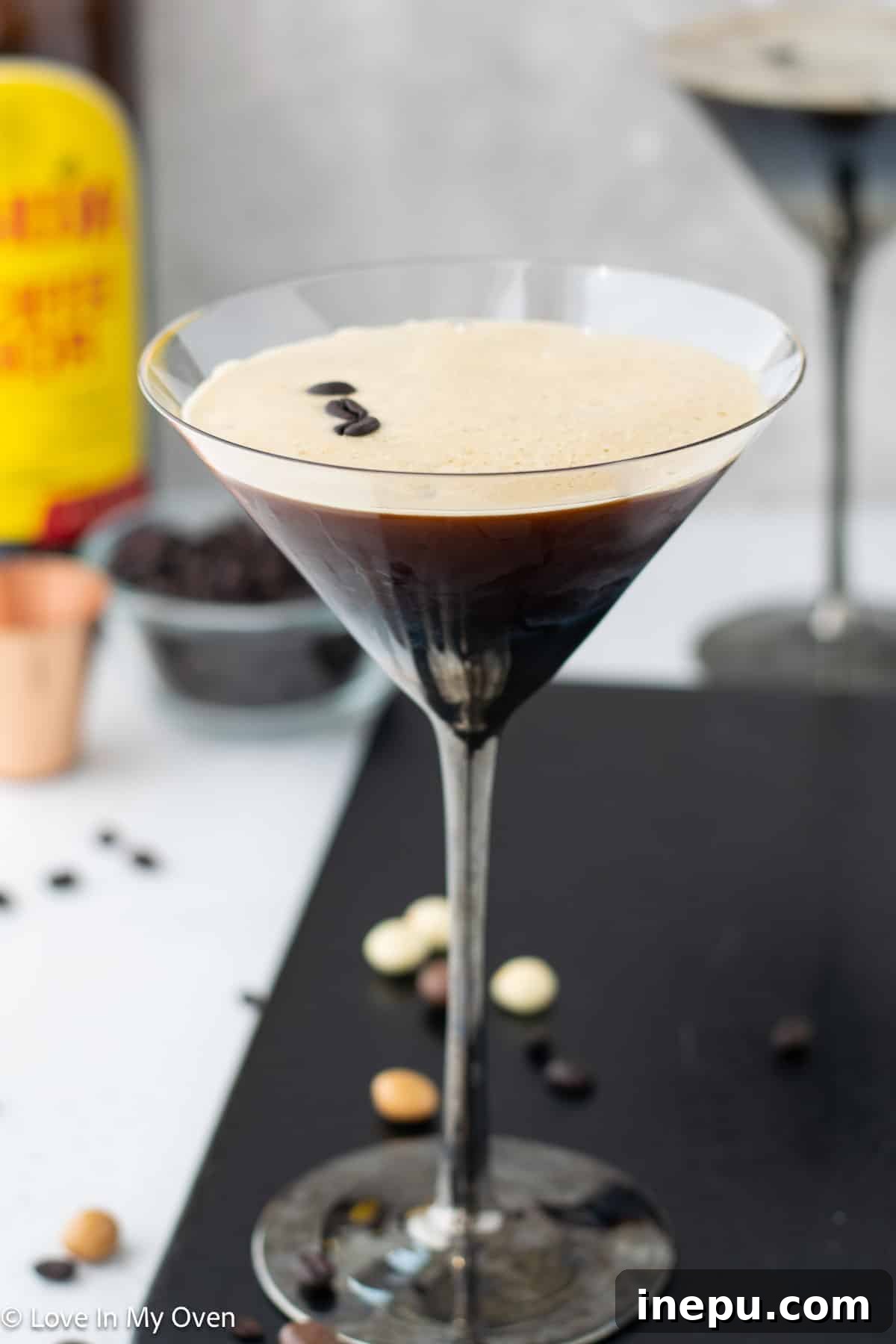 Classic Vodka Espresso Martini topped with a rich, creamy foam and garnished with three whole espresso beans, served in a stylish martini glass.