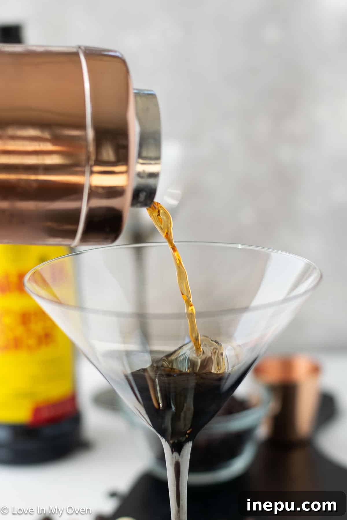 A cocktail shaker filled with ice and the ingredients for an espresso martini, being vigorously shaken to create the perfect foam.