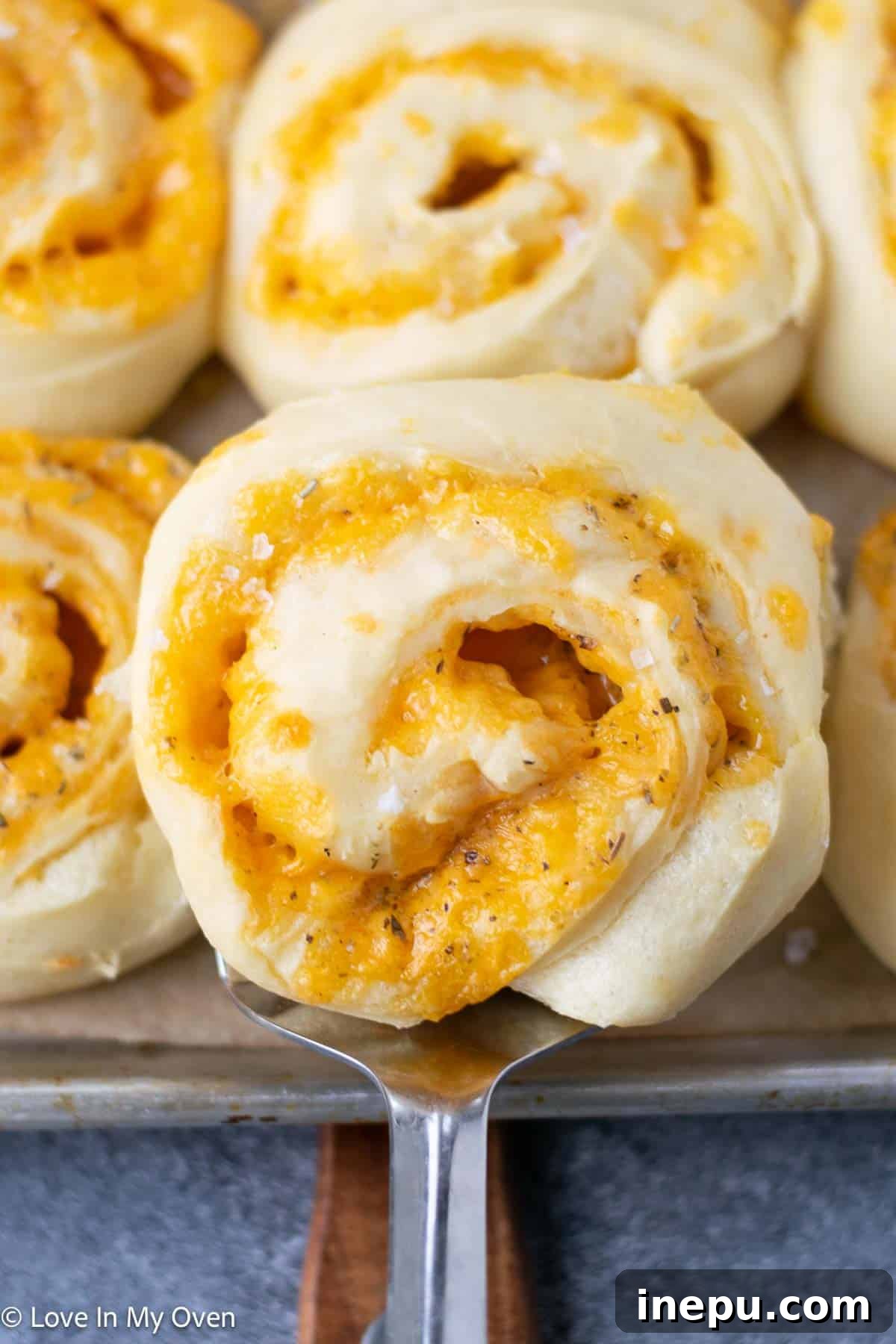 overhead shot of a basket of cheese rolls with one roll broken open to show the soft interior