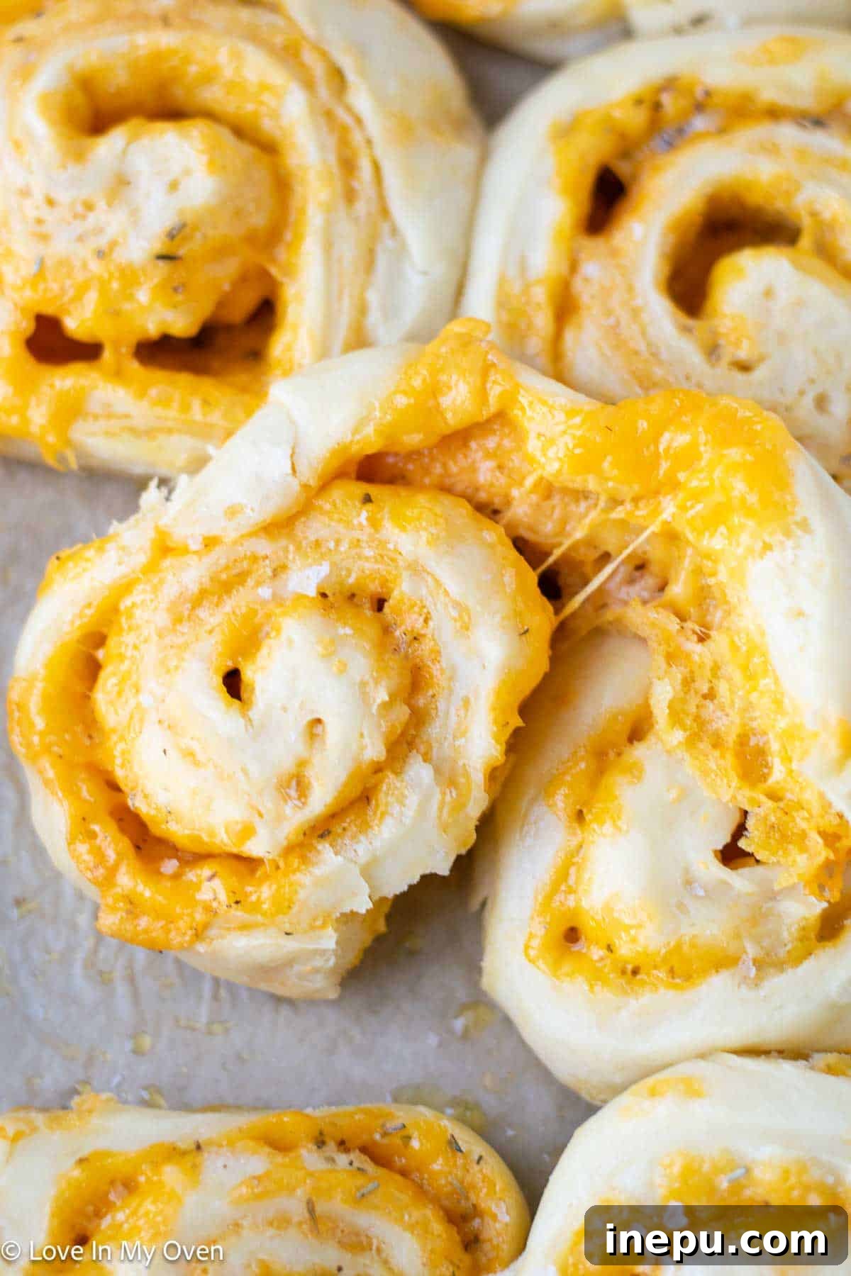 several golden cheese rolls stacked on a wooden board