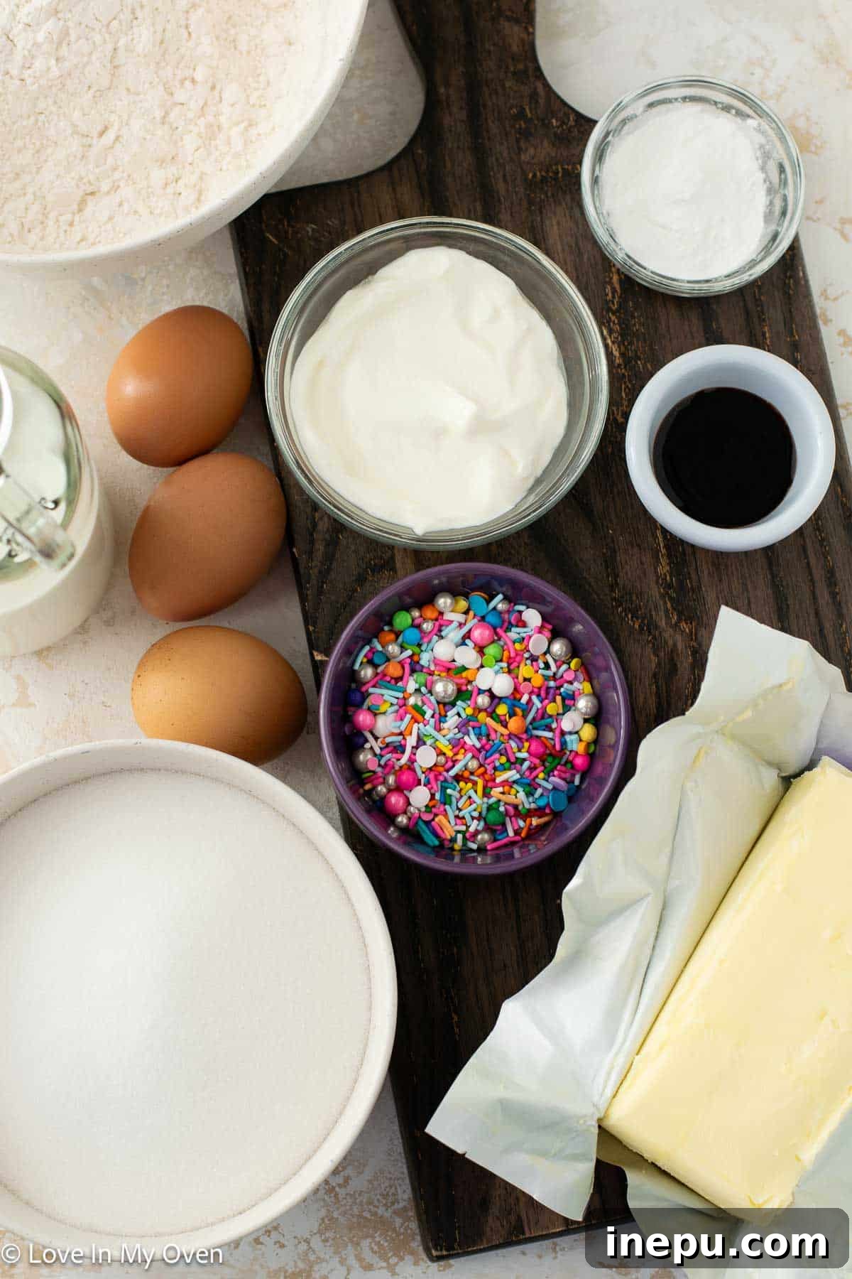 Sweet Stacks 3 Close-up of baking ingredients for sprinkle cake, including butter, sugar, flour, and sprinkles.