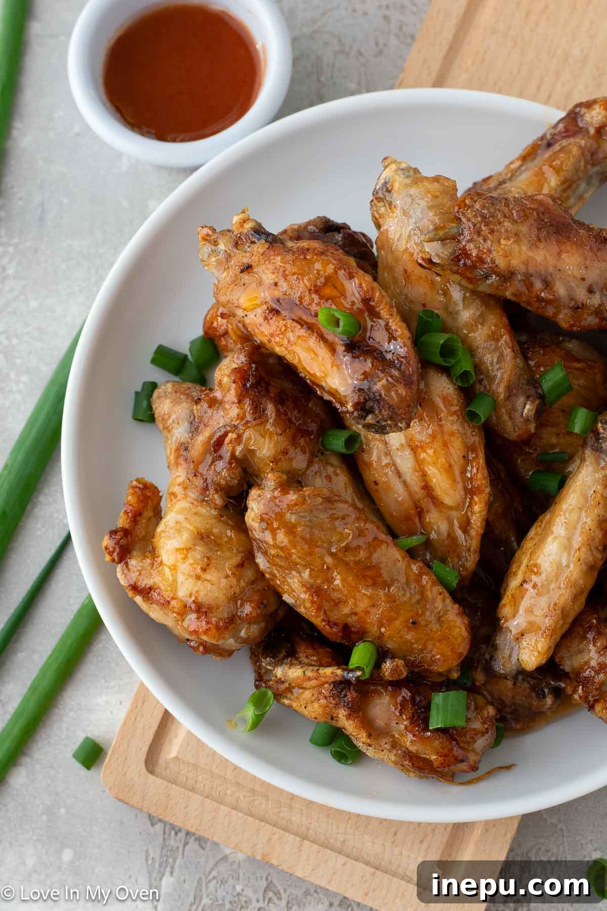 A vibrant platter of hot honey chicken wings garnished with fresh herbs