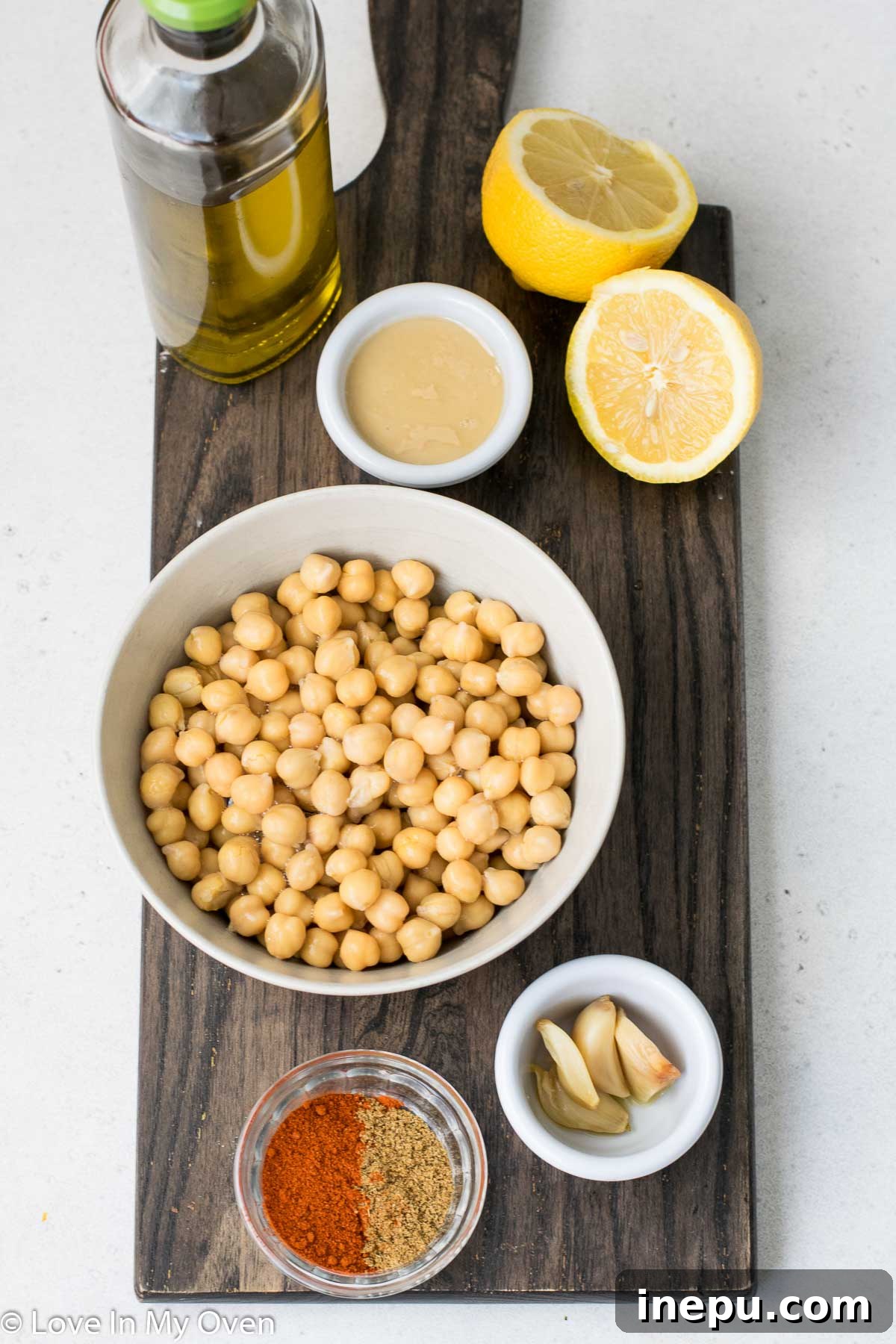 Golden Roasted Garlic Hummus 4 Various ingredients for Roasted Garlic Hummus, including chickpeas, lemons, tahini, and spices, arranged on a kitchen counter
