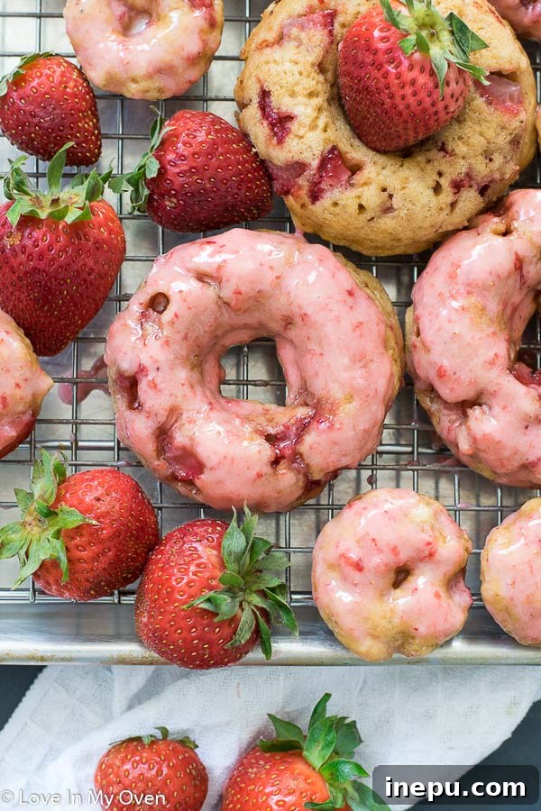 Two baked strawberry donuts stacked on a plate