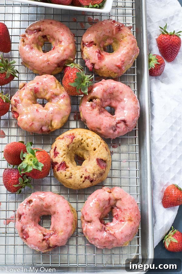 Variety of baked strawberry donuts on a wooden board