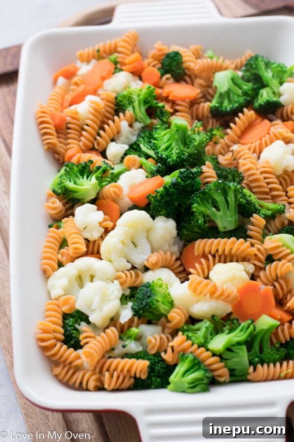 Mixing cooked vegetables and pasta in a casserole dish