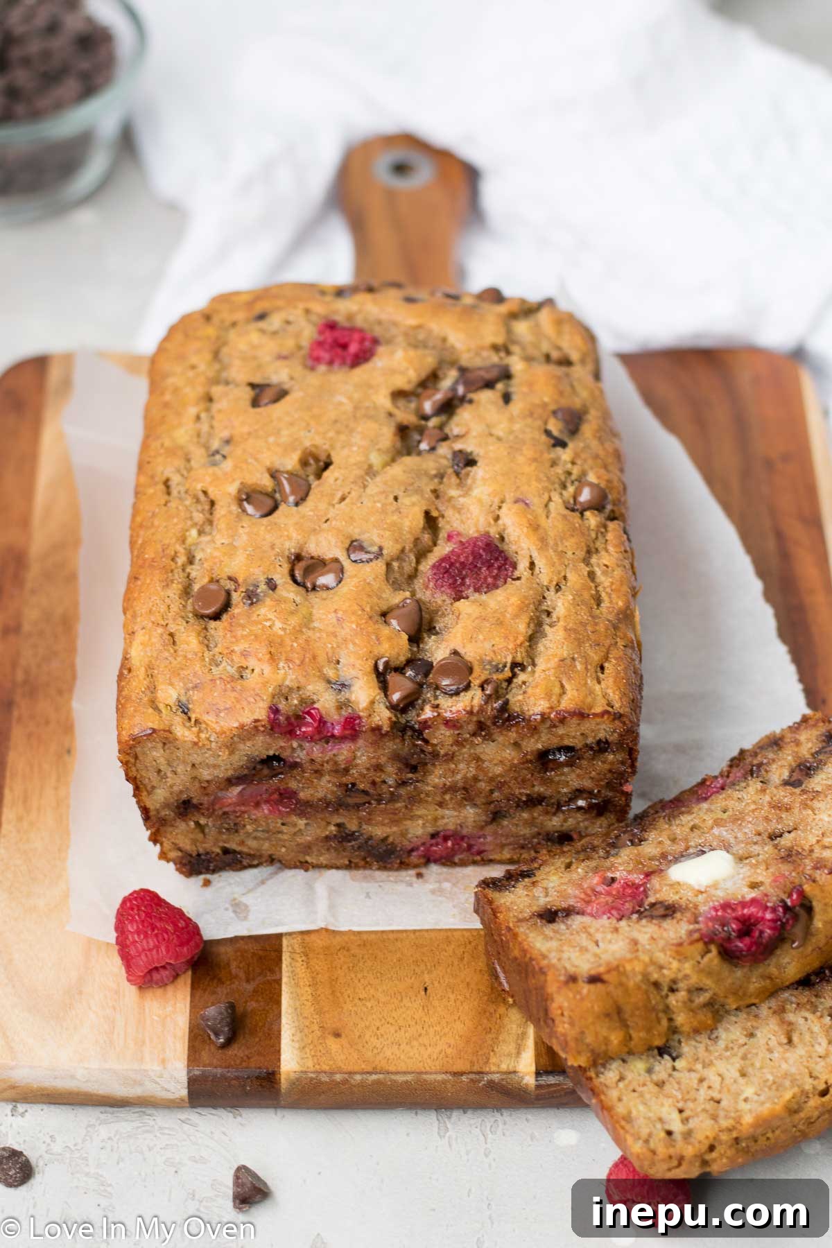 Stack of raspberry banana bread slices with fresh raspberries
