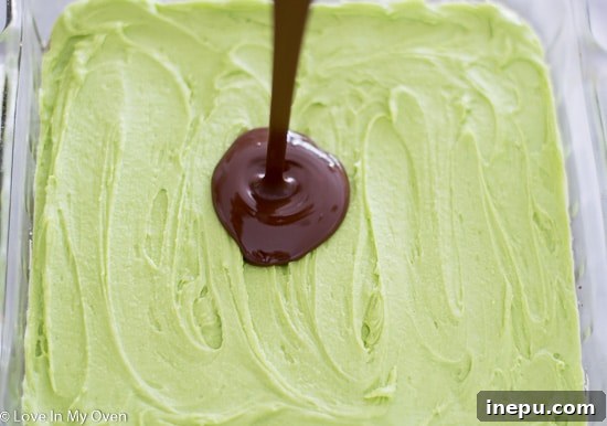 Final chocolate layer being spread over the mint Nanaimo bars