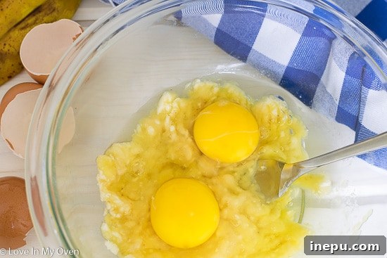 Dynamic Duo Flapjacks 5 Step 2: Adding eggs to mashed banana for pancake batter.