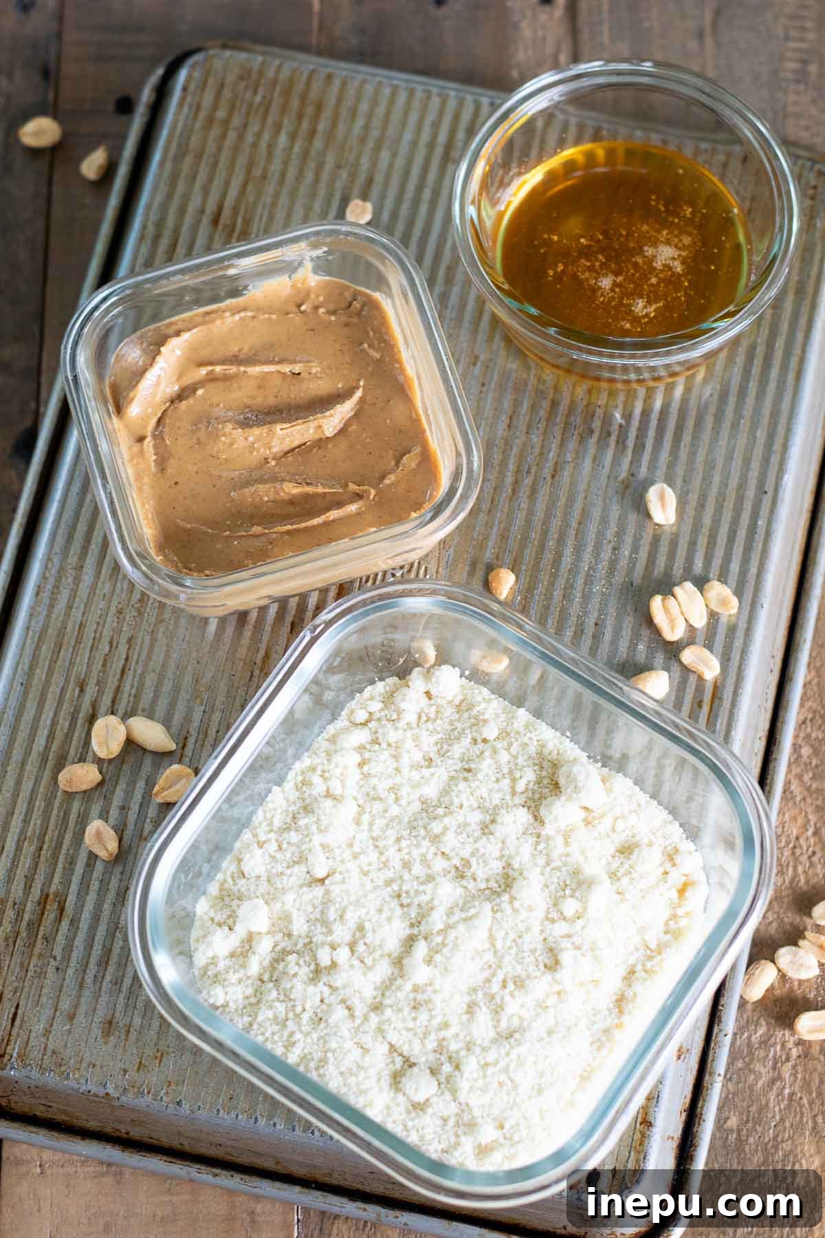 Close-up of the three ingredients used for peanut butter cookies: almond flour, peanut butter, honey