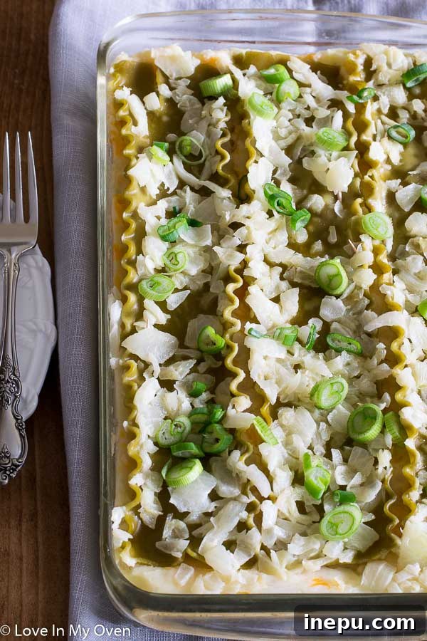 Effortless Perogies 8 Slice of Lazy Perogy Casserole on a plate, garnished with green onions and sour cream.