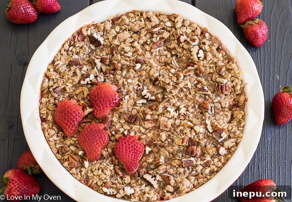 Strawberry Streusel Baked Oats 3 Close-up of baked oatmeal with a spoonful removed, revealing baked strawberries and a crumbly streusel topping