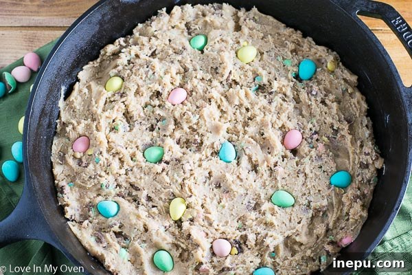 Folding crushed mini eggs into cookie dough with a spatula