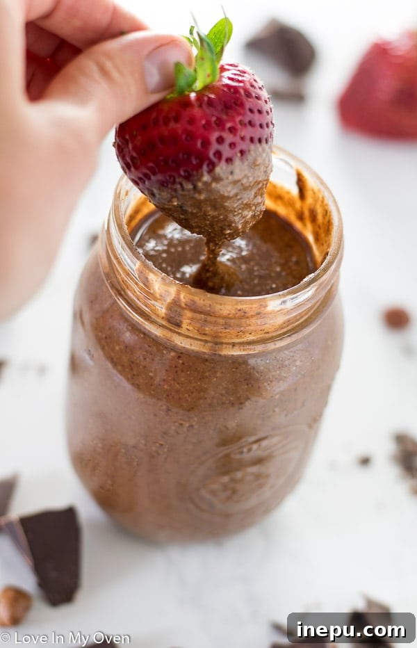 A jar of homemade Notella with a spoon, showing its creamy texture, on a rustic background.