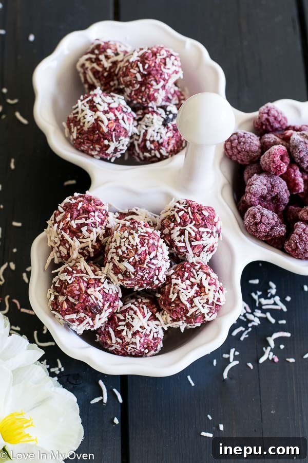 Close-up of a stack of raspberry coconut bites, highlighting their soft texture and the flakes of coconut, ready to be enjoyed.