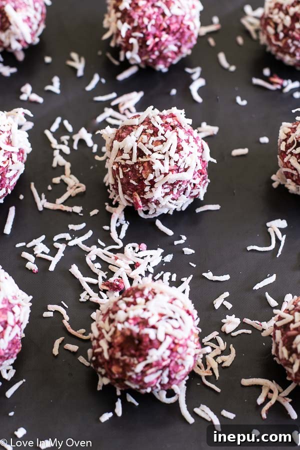 A close-up of the raspberry coconut mixture in a food processor, showing the blended texture before rolling it into bites.